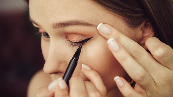 803464472 Woman doing makeup and painting black arrows
