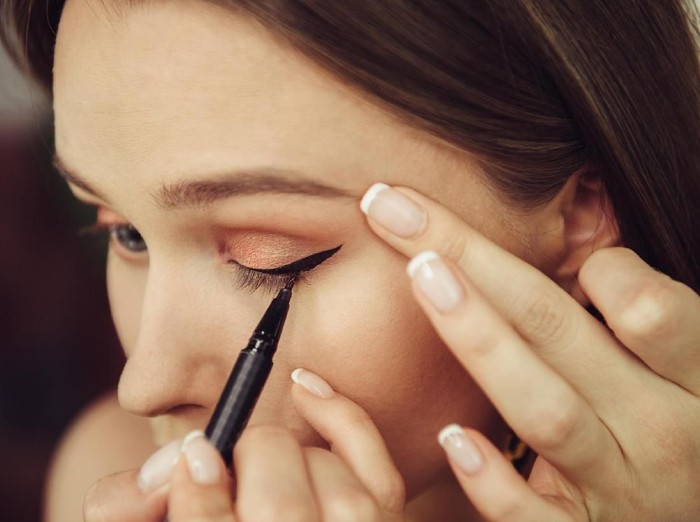 803464472 Woman doing makeup and painting black arrows