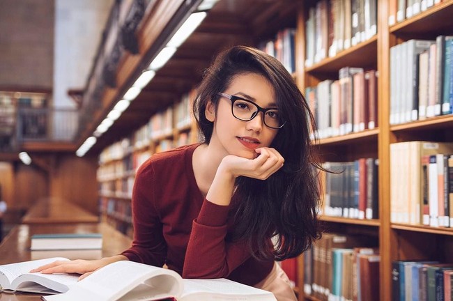 Sexy yet Smart and Elegant, gaya Velove Vexia berpose di perpustakaan memakai sweater merah dan kacamata. Foto: Dok. Instagram Velove Vexia