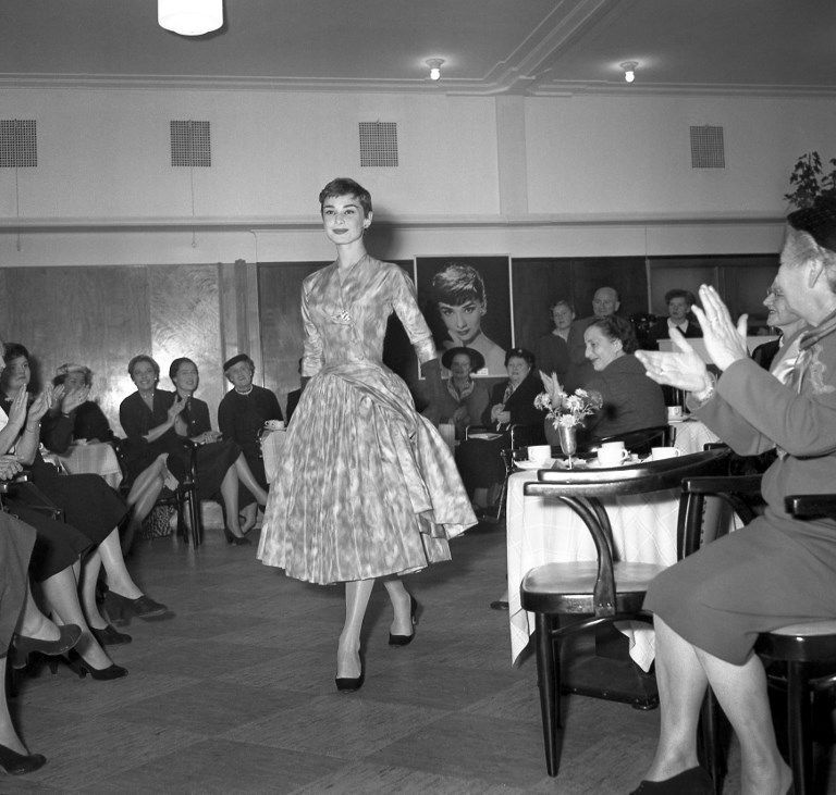 L'actrice Audrey Hepburn présente une création du couturier Hubert de Givenchy, lors d'un défilé de mode, en novembre 1954, à Amsterdam.Actress Audrey Hepburn shows a Givenchy model, during a fashion show, in November 1954, in Amsterdam. / AFP PHOTO
