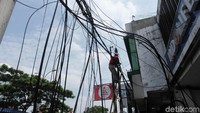 Petugas memanjat tiang untuk membersihan kabel yang semrawut.