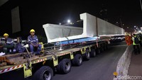 Para pekerja mengirim U-Shape Girder ke lokasi proyek LRT Jabodebek menggunakan truk.