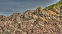 Puncak Siccar Point adalah batu-batu berwarna kemerahan. Terdapat warna kontras antara garis-garis vertikal dan lapisan horisontal bebatuan pasir di atasnya (John Van Hoesen/BBC Travel)