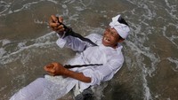 Seorang pria menggunakan keris dalam melasti. Foto: REUTERS/Johannes P. Christo