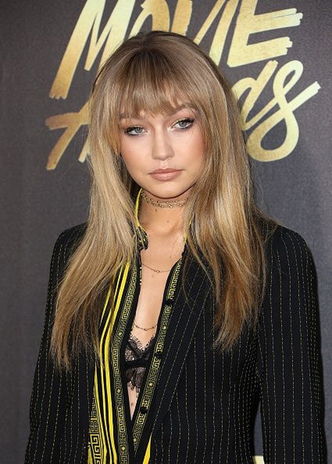 Tak jarang, Gigi Hadid juga bermain dengan wig. Kali ini, ia memakai wig rambut panjang dengan poni. Foto: Getty Images