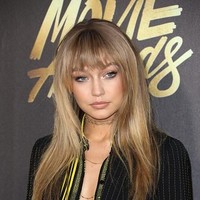 Tak jarang, Gigi Hadid juga bermain dengan wig. Kali ini, ia memakai wig rambut panjang dengan poni. Foto: Getty Images