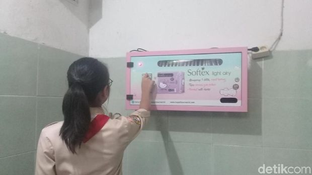 Seorang siswi memasukkan koin ke dalam vending machine pembalut di toilet putri SMPN 115.