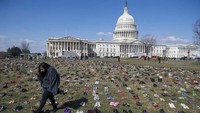 Seorang warga melintas di antara sepatu-sepatu yang berjajar (Foto: AFP PHOTO / SAUL LOEB)