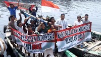 Para nelayan membentangkan spanduk menolak hoax si atas perahu.
