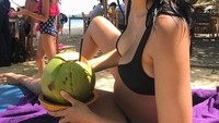 Saat hamil 29 minggu, Dominique menikmati babymoon di Bali. Usai nyebur ke pantai, ia menyesap kelapa muda yang bikin segar! Foto: Instagram dominiquediyose