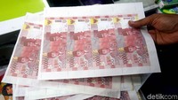 Polisi menunjukkan lembaran-lembaran uang palsu yang belum dipotong.