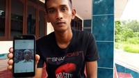 Anak pertama Zaini, Saiful Toriq, menunjukkan foto ayahnya. (Foto: Zaenal Effendi/detikcom)