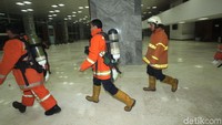 Para petugas bergegas masuk menggunakan seragam oranye, sebagian lagi mengenakan tabung oranye di punggung.