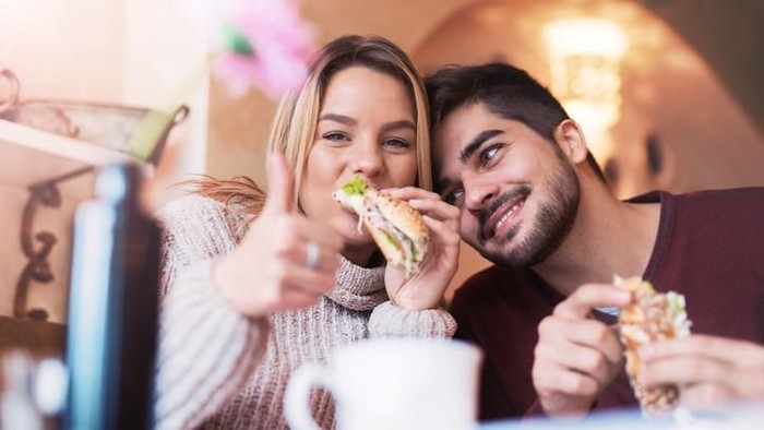Portrait of an happy couple.They are laughing and eating pizza and having a great time.