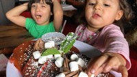 Gambar ini walau diambil secara tidak sengaja, tapi seperti bercerita, ya. Sang kakak terlihat tidak terima karena si adik mengambil marshmallow yang ada di atas pancake berwarna oren itu. Lucu, ya! Foto: Instagram @foodbabyny