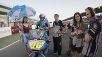 Langit di atas Sirkuit Losail mulai gelap, Joan Mir bersiap memacu motornya ditemani tim dan pastinya seorang umbrella girl (Mirco Lazzari gp/Getty Images)