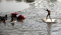 Seorang anak berselancar menggunakan styrofoam.