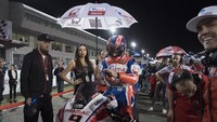 Meski gelap sudah datang dan suhu udara sama sekali tidak panas, umbrella girl ini setia menemani para pebalap. Lengkap dengan payung yang terbuka (Mirco Lazzari gp/Getty Images)