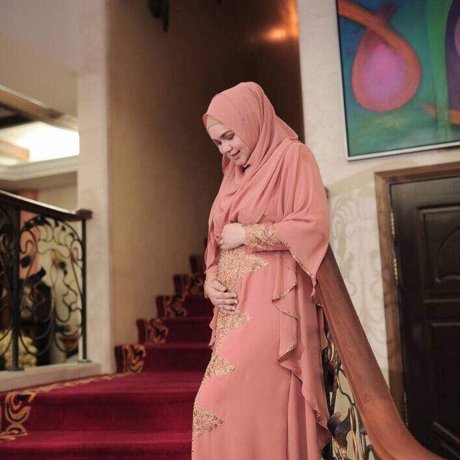 Saat mengumumkan kandungannya. Ia tampak sangat bahagia dan penuh syukur. Ia tampil dengan bernuansa warna tangerine dari hijab hingga dress yang ia pakai. Pada postingan tersebut, ia memohon izin kepada para pengikutnya untuk bisa full istirahat selama kehamilannya. Foto: Instagram/ctdk