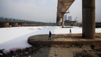 Sungai Yamuna tiba-tiba menjadi putih dan dipenuhi buih. Terlihat dua orang pria berdiri di bawah jembatan melihat sungai yang berada di tepi New Delhi, India, itu.  (Foto: REUTERS/Adnan Abidi)