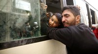 Seorang ayah memeluk anaknya yang akan dievakuasi. REUTERS/Bassam Khabieh.