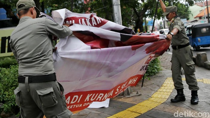 Petugas pengawas Pemilu menurunkan spanduk parpol di Jl Letjen Suprapto, Cempaka Putih, Jakarta. Spanduk itu milik Partai Gerindra, Demokrat, dan Perindo.