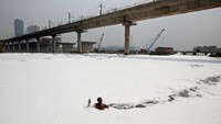Seorang pria terlihat berenang di tengah buih-buih Sungai Yamuna. Pria itu terlihat mengumpulkan sampah-sampah di sungai tersebut sehari sebelum Hari Air Dunia. (Foto: REUTERS/Adnan Abidi)