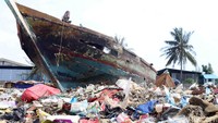 Selain sampah plastik, ada juga bangkai perahu yang teronggok di pantai.