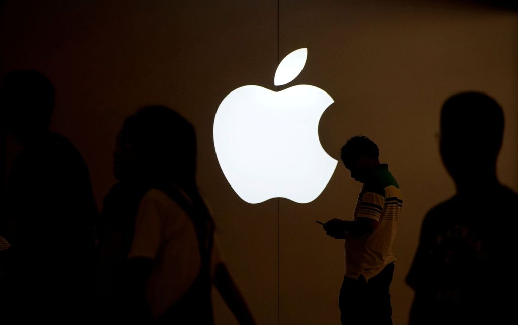 FILE PHOTO: A man looks at the screen of his mobile phone in front of an Apple logo outside its store in Shanghai, China on July 30, 2017.   REUTERS/Aly Song/File Photo