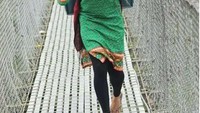 Wanita penjual sayur ini bernama Tarkariwali. Dengan mengenakan baju hijau, ia terlihat sedang mengangkat keranjang yang berisi sayuran di atas jembatan. Foto: Istimewa