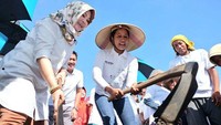 Dalam kesempatan itu, Rini menggunakan topi petani atau caping dan secara simbolis ikut mencangkul tanah dalam program padat karya cash. Pool/Humas Kementerian BUMN.