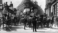 Seorang polisi di London tengah mengatur lalu lintas dari para omnibus (kendaraan yang berhenti). General Photographic Agency/Getty Images.