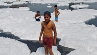Anak-anak di India main busa di sungai yang kotor.
