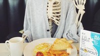 Ini gaya keren Skellie ketika sedang menikmati sarapan telur mata sapi, roti, dan kentang goreng, lengkap dengan secangkir kopi. Foto: Instagram @omgliterallydead