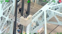 Pria itu tampak mengenakan jaket hijau dan celana panjang hitam. Beberapa petugas coba membujuknya agar turun. (Foto: Dok. CCTV via The Independent)