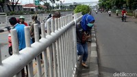 Beberapa warga menyeberang jalan dengan menerobos pagar pembatas, Selasa (27/3/2018).