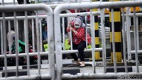 Seorang warga menerobos di antara pilar-pilar pagar.