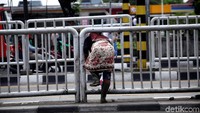 Seorang warga menerobos pagar pembatas untuk menyeberang jalan.