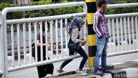 Warga berhenti sejenak untuk menunggu lalu lintas sepi.