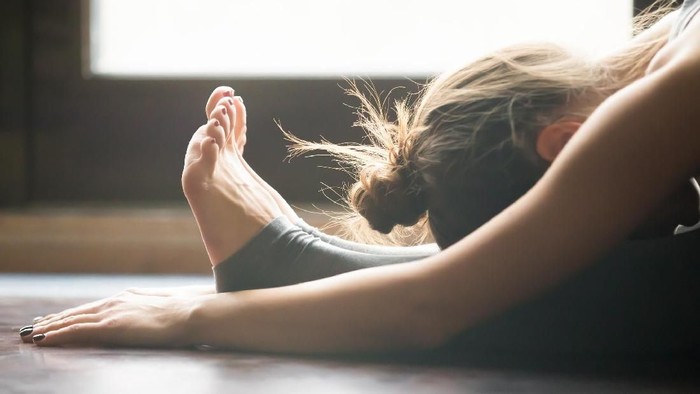 820933744 Young woman doing yoga twisting mat indoors near window