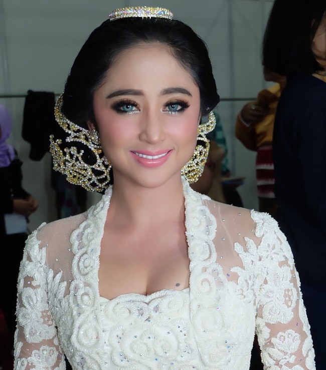 Agar terlihat lebih glamour, sang hair stylist menerapkan tiara kecil di bagian atas rambut dan tusuk konde bertabur bebatuan di bagian kiri dan kanan sanggul. Penampilan Dewi Persik ini pun banjir pujian. Sebagian besar menyebutnya ayu dan cantik. Foto: Instagram @AndruwSpun
