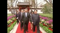 Kim Jong Un dan Xi Jinping berbincang sambil berjalan di taman (Foto: CCTV via Reuters TV)