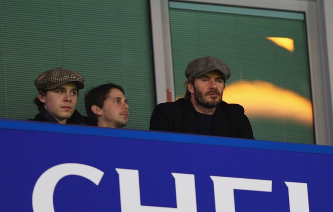 David Beckham dan Brooklyn kompak mengenakan topi newsboy alias loper koran saat menyaksikan laga antar Chelsea dan Manchester United di London, Inggris, Maret 2017 lalu. (Foto: Getty Images)