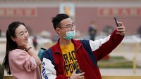 Meski dikepung debu, Tiananmen Square tetap dikunjungi turis. Ada juga yang tidak memakai masker