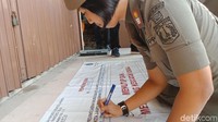 Seorang anggota Satpol PP menulisi spanduk yang akan dipasang di Alexis.