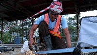 Petugas memotong seng yang akan dipasang di sekitar lokasi longsor.