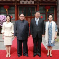 Ri Sol-ju tampil stylish dengan setelan aksen peplum dan lengan bell-sleeve. Padanan busana monokrom yang dipercantik bros bunga di dada. Foto: Reuters