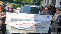 Satpol PP juga membawa spanduk bertuliskan Menutup dan Melarang Kegiatan Usaha.