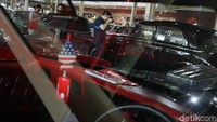 Dari balik mobil, terlihat pengunjung antusias memperhatikan mobil jadul yang dipamerkan.