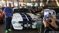 Bapak dan anak berpose bareng di mobil Ford Mustang berkelir putih dengan strip biru. Mobil-mobil ini jadi obyek foto pengunjung.